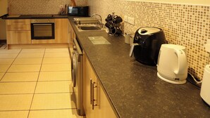 A kitchen with a microwave, sink, coffee maker, and a kettle. - Holiday Cottage 1 (Skegness)