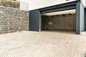 A paved outdoor area with a stone wall and a covered entrance. - Scandinavian Villa • Infinity Pool • Ocean view • Office with a View (Ribeira Brava)