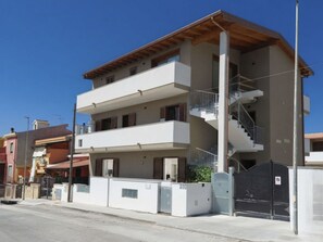Ein mehrstöckiges Wohngebäude mit einer zentralen Treppe, Balkonen und einem verschlossenen Eingang.