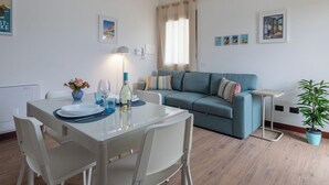 Un salon moderne avec un canapé, une table à manger et des chaises, ainsi qu’une plante en pot.