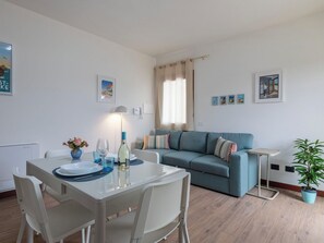 Ein modernes Wohnzimmer mit einer Couch, einem Esstisch mit Stühlen und einer Topfpflanze.