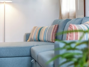 Ein modernes Wohnzimmer mit Sofa, gestreifte Kissen, einer Stehlampe und einer Pflanze.