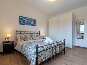 A bedroom with a bed, nightstands, a wardrobe, and a painting on the wall. - Nice apartment for 4 people with A/C, WIFI, TV and balcony (Sorso)