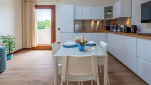 Une cuisine moderne avec des meubles blancs, un plan de travail en bois et un coin repas avec une table mise pour deux personnes.