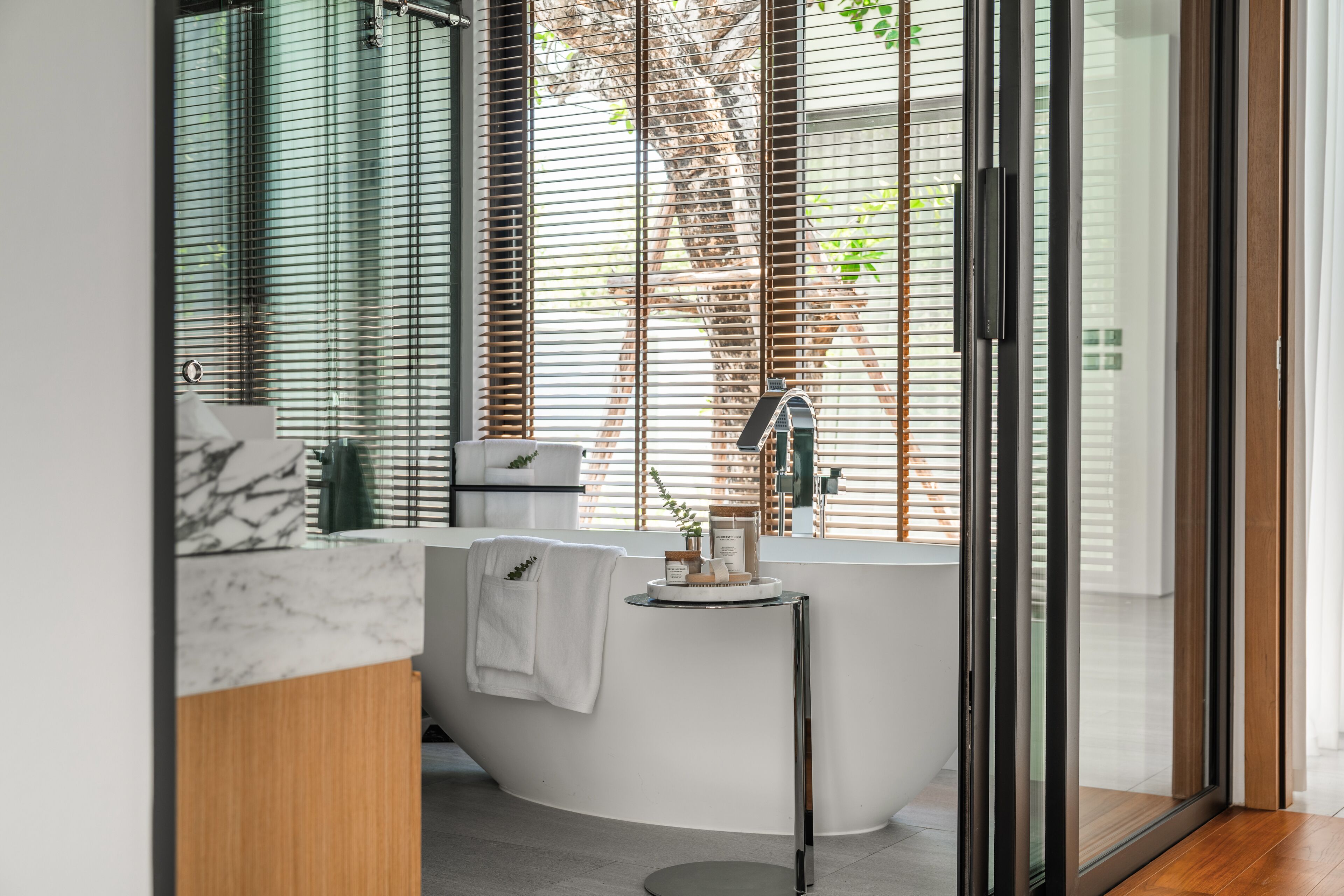 A modern bathroom with a freestanding bathtub, a towel rack, and a glass shower enclosure.