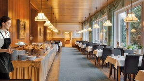Ein Restaurant mit einer langen Theke, mehreren Tischen und hängenden Pendelleuchten.
