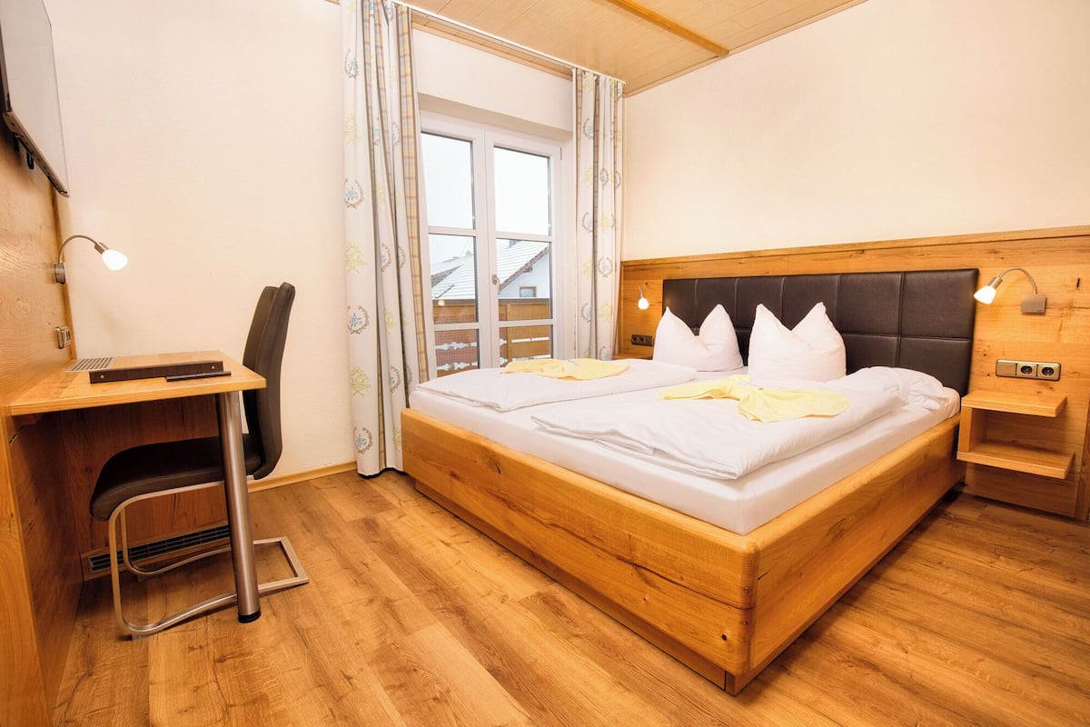 A bedroom with a wooden bed, a desk, and a chair.