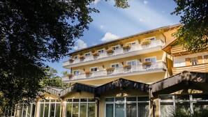 Ein mehrstöckiges Hotel mit Balkonen, großen Fenstern und einem gepflegten Rasen.
