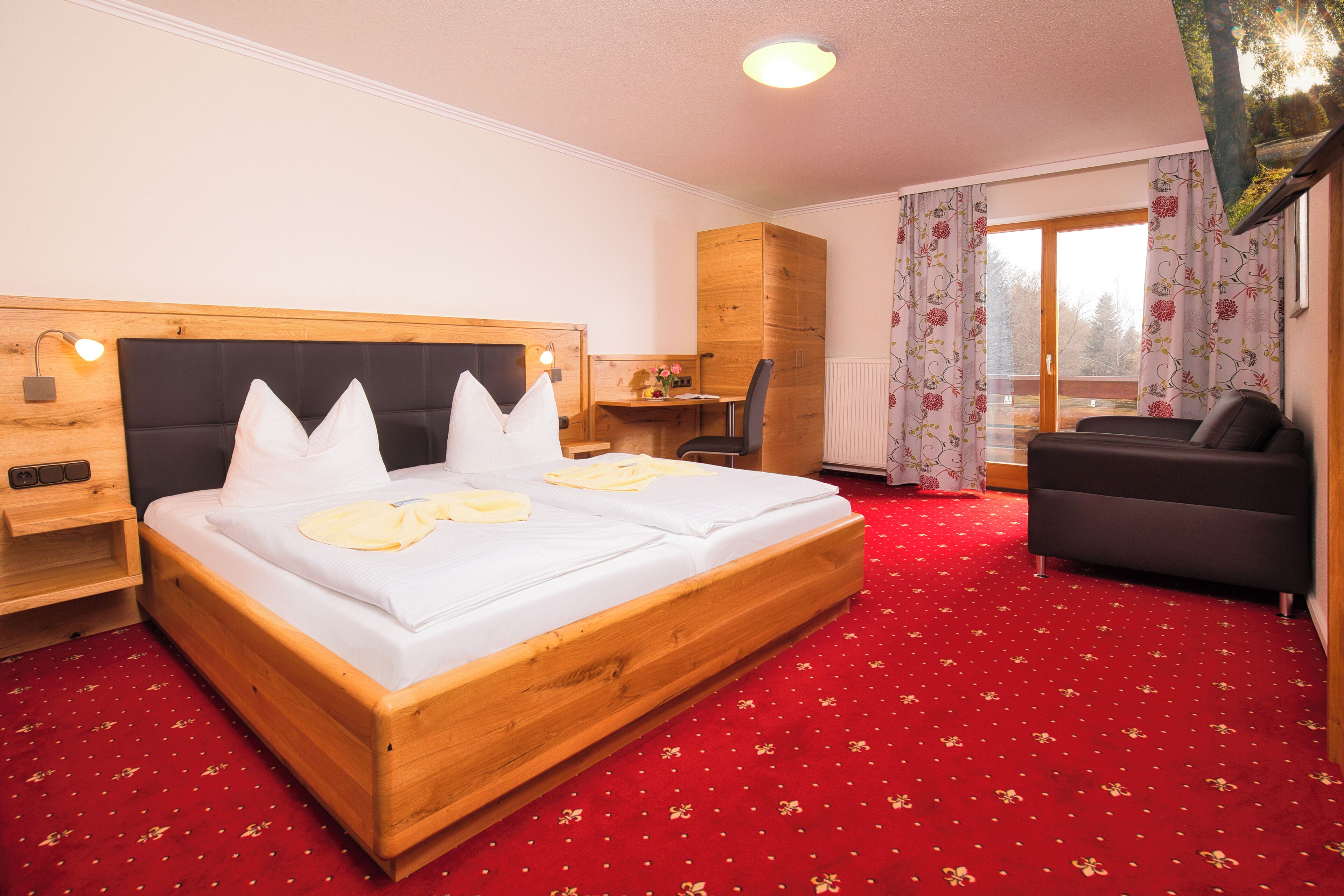Quarto de hotel com uma cama grande, uma escrivaninha, um sofá e vista para o exterior.