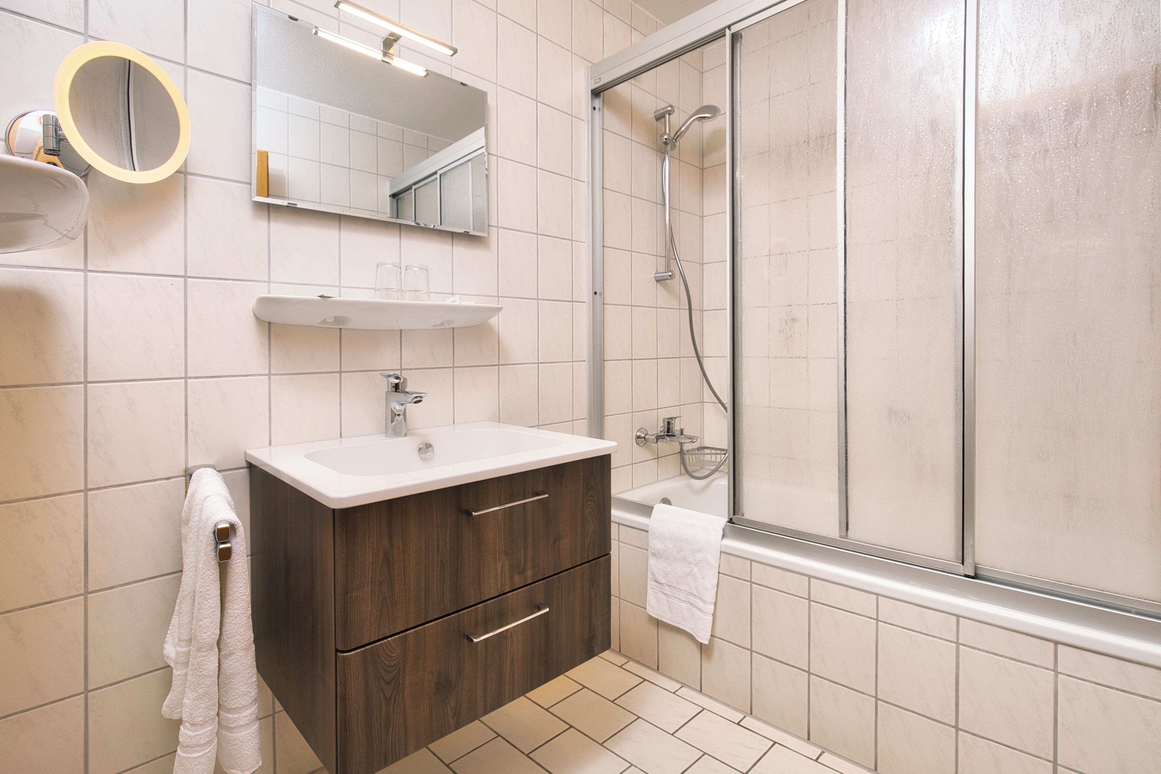 A modern bathroom with a shower, a sink, and a mirror.