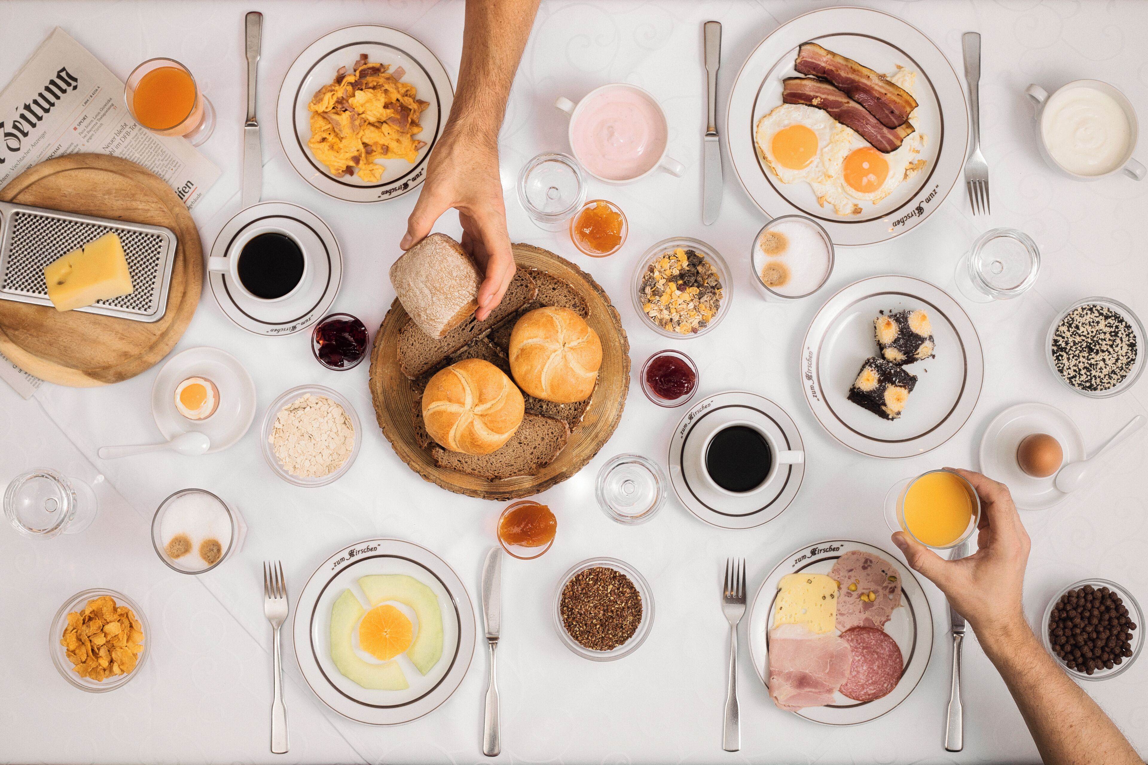A breakfast setting with various food items and utensils on a table.