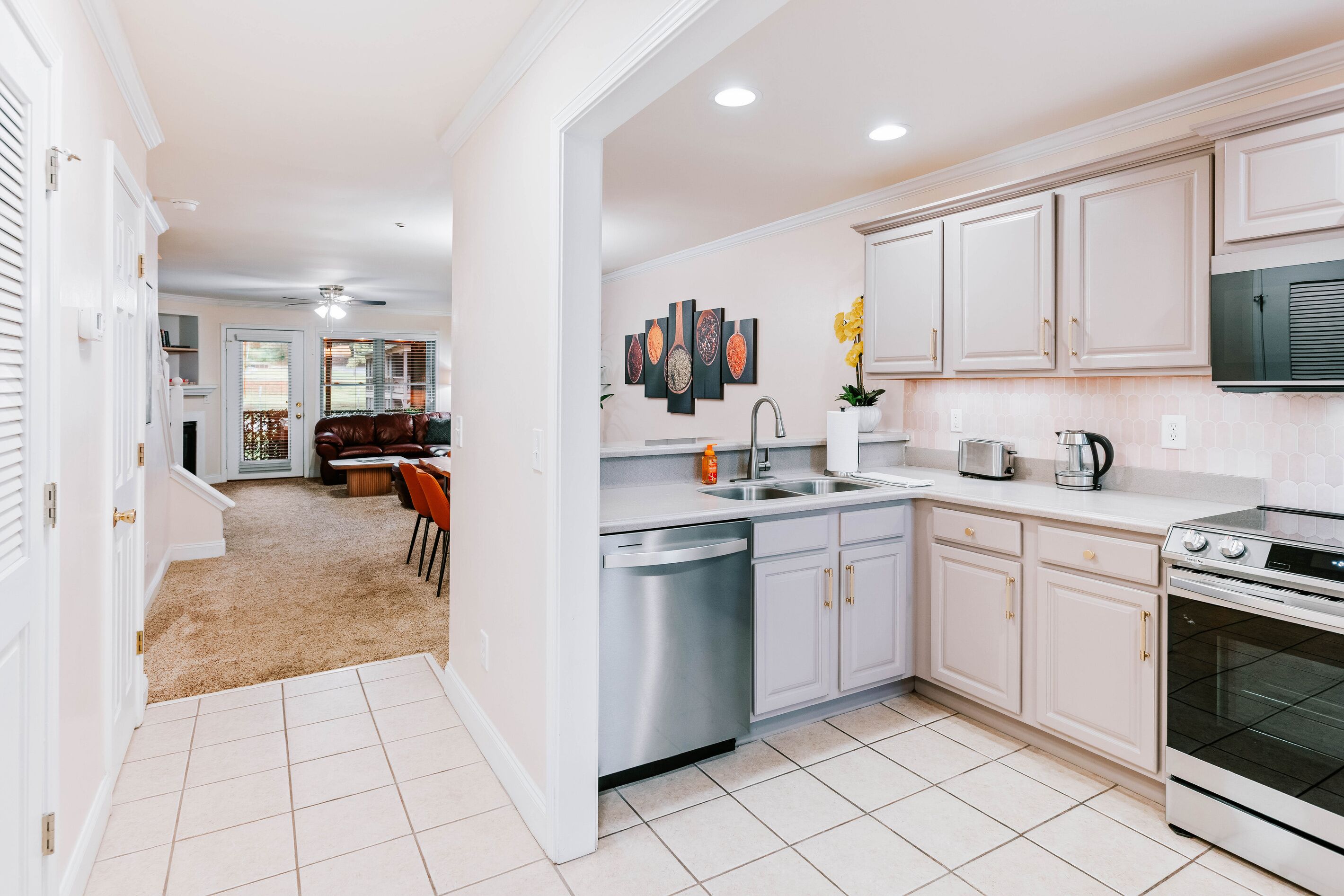 A modern kitchen with white cabinetry, stainless steel appliances, and a tiled floor.
