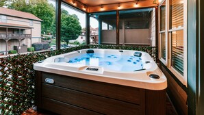 Ein Whirlpool mit Bedienfeld, umgeben von einer Holzterrasse und einem Metallgeländer, mit Blick auf eine Wohngegend.