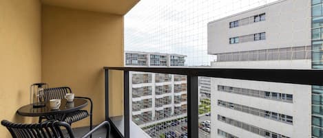 Un balcón con una mesa y sillas, con vistas a un paisaje urbano con edificios modernos.