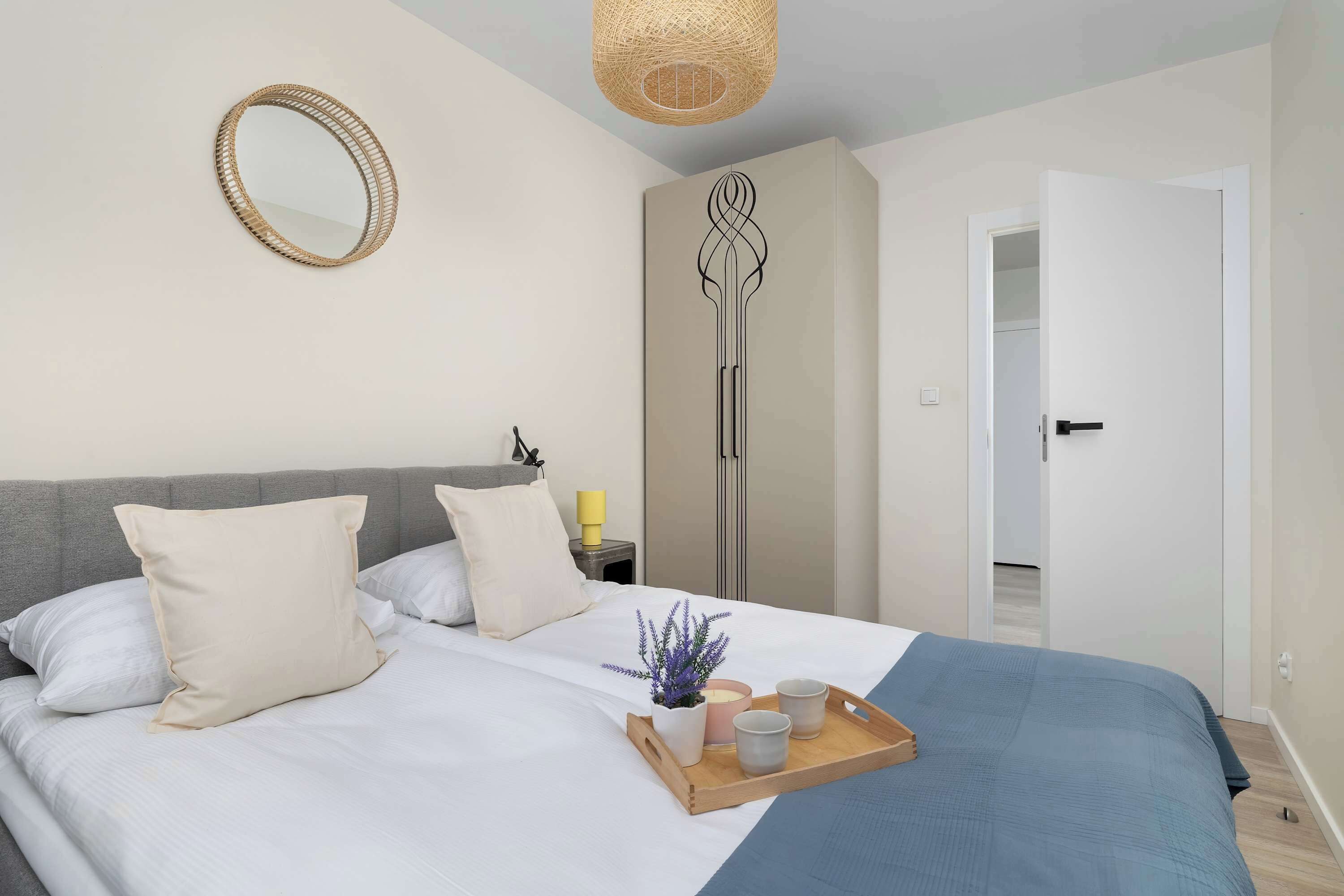 A modern bedroom with a bed, bedside table, and a wardrobe.
