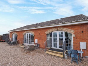 A building with a tiled roof, brick walls, and a gravel driveway. - Holiday Cottage 2 (Skegness)