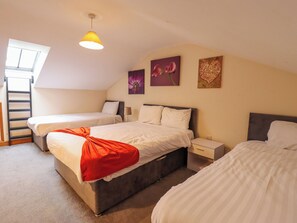 A bedroom with two beds, a window, and artwork on the wall. - Holiday Cottage 2 (Skegness)