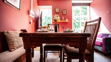 A dining area with a wooden table, chairs, a bench, and a vase with flowers.