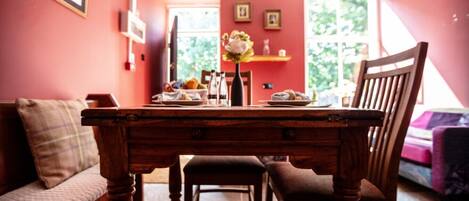 Un coin repas avec une table en bois, des chaises, un banc et un vase rempli de fleurs.