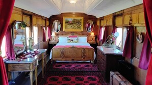 Quarto tradicional com uma cama grande, paredes de madeira, um candelabro e um quadro sobre a cama.