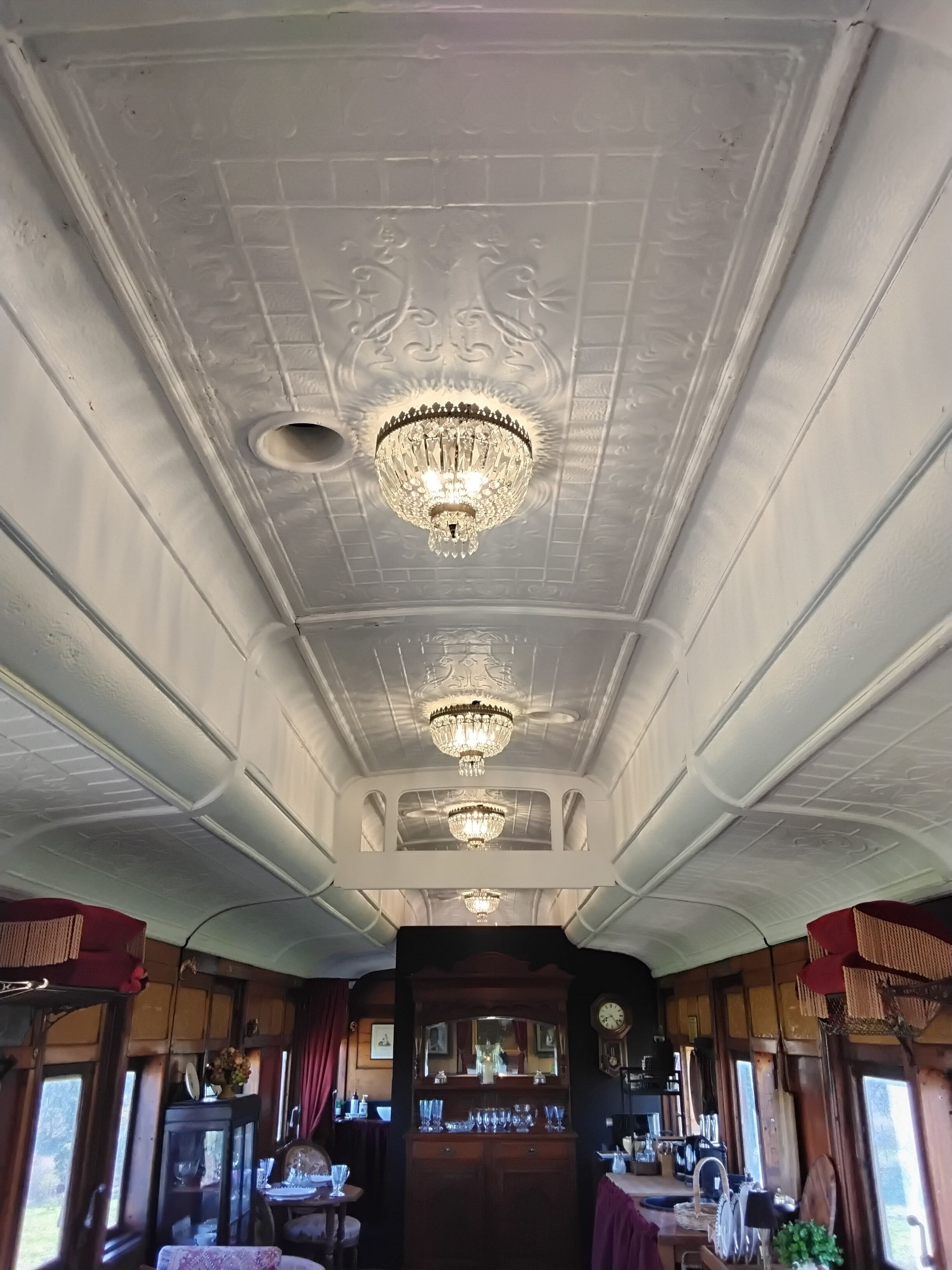 A room with a high ceiling, ornate plasterwork, and three chandeliers.