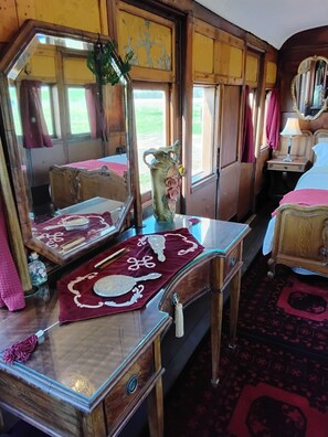 A room with a wooden bed, a dresser with a mirror, and a window with curtains.