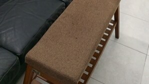 A living room with a black leather sofa, a brown bench, and a wall-mounted cabinet. - RESIDENCE BELLE VUE PALMERAIE (ABIDJAN)