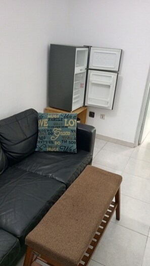 Una sala de estar con un sofá de cuero negro, un banco marrón y un mueble de pared.