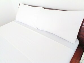 Una cama con ropa de cama blanca y cabecera de madera.