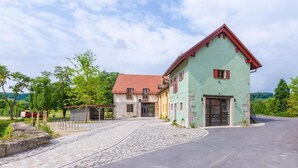 A two-story building with a red roof and a green facade, a cobblestone driveway, and a paved road leading to it. - Alter Hafen Marktsteft (Marktsteft)
