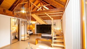 A spacious living area with a wooden staircase, a large TV, and a modern light fixture. - Alter Hafen Marktsteft (Marktsteft)