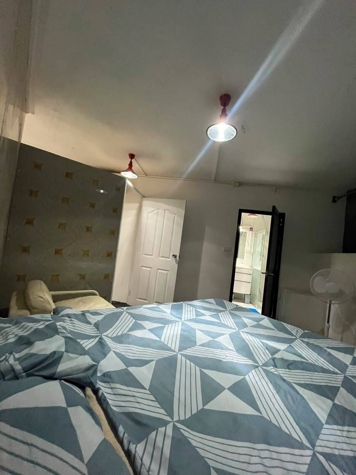 A bedroom with a bed, a door, a ceiling fan, and a light fixture.