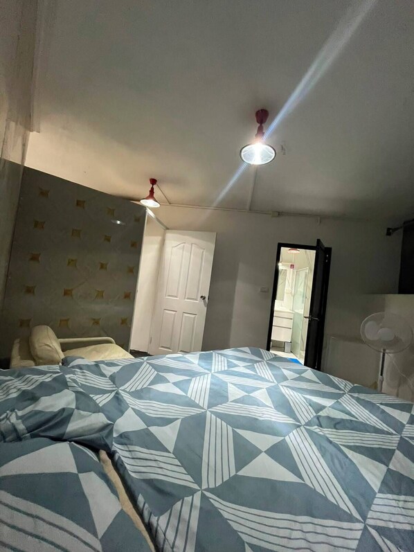 A bedroom with a bed, a door, a ceiling fan, and a light fixture.