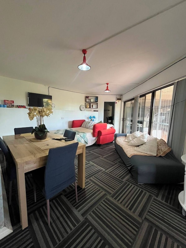 A modern living space with a dining area, a sofa, and a bed.