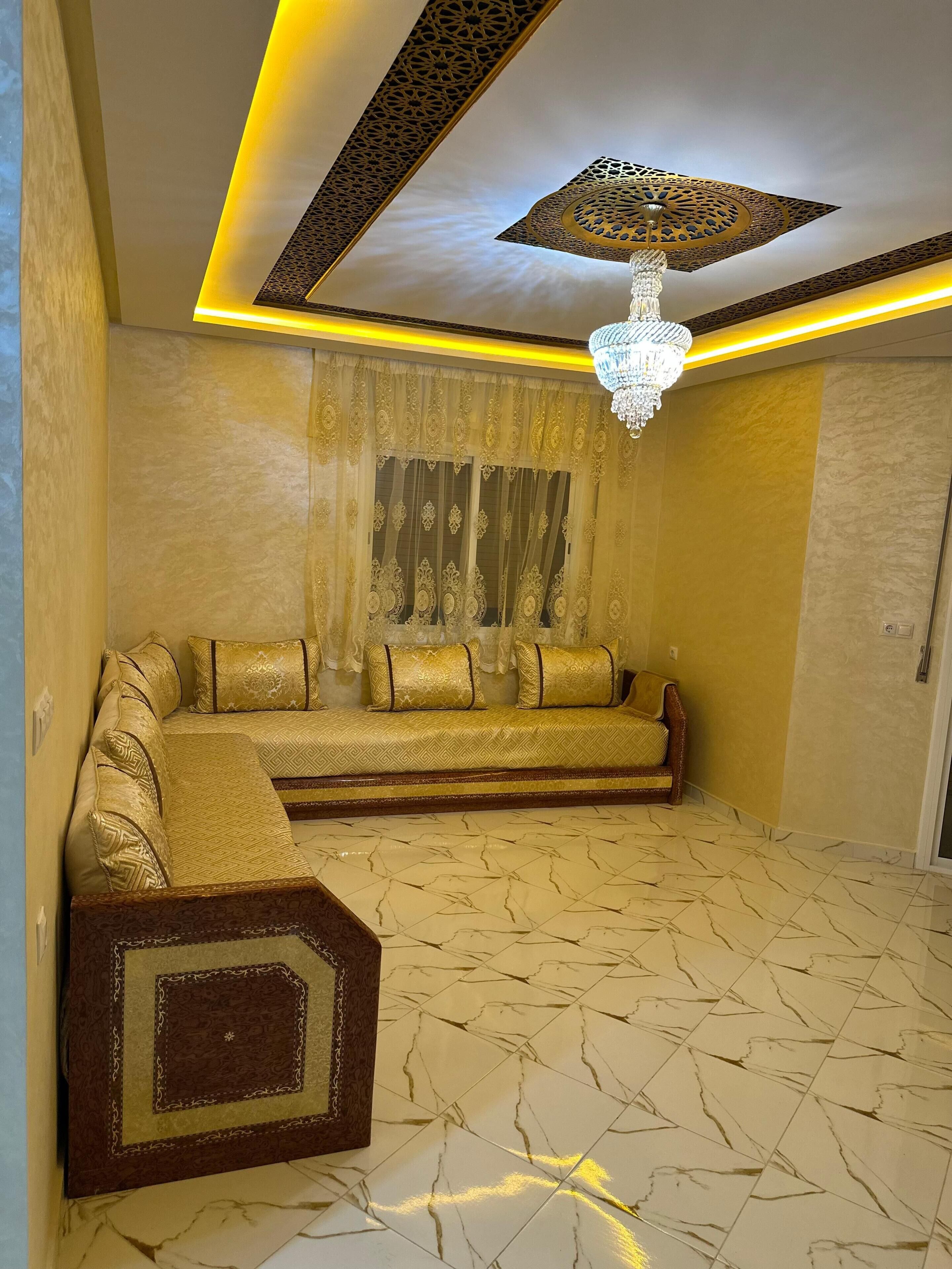 A room with a sofa set, a chandelier, and patterned walls.