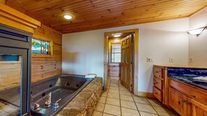 Une salle de bain avec un lavabo en pierre, des meubles en bois et une douche à parois de verre.