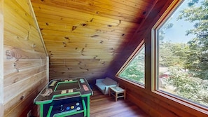 A wooden interior with a table and bench, a large window, and a view of greenery. - Moonlit Mountain Retreat | Mountain Views, Hot Tub & Fantastic Game Room (Sevierville)