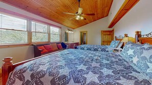 Une chambre avec un grand lit, un plafond en bois et une fenêtre avec des stores.