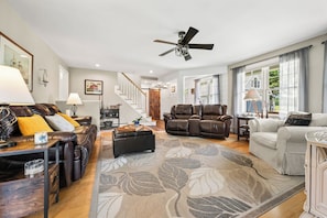 A spacious living room with leather sofas, a ceiling fan, and a large window providing natural light. - Mingo Manor | Across from Mingo Springs Golf Course!! (Rangeley)