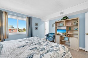 Ein Schlafzimmer mit einem Bett, einem Sessel, einem Fernseher und einem Bücherregal.
