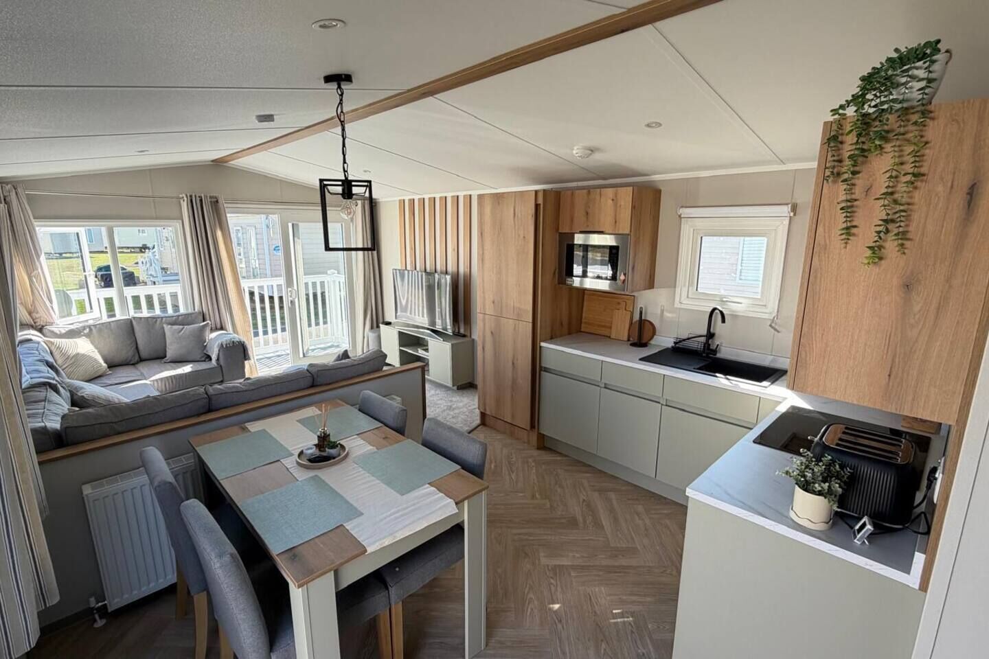 A compact living space with a sofa, dining table, kitchenette, and a TV.