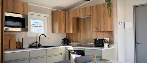 Une cuisine compacte dotée de meubles en bois, d’un four à micro-ondes, d’une bouilloire et d’un grille-pain.