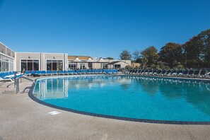 Ein Swimmingpool mit blauen Liegestühlen und einem Gebäude im Hintergrund.
