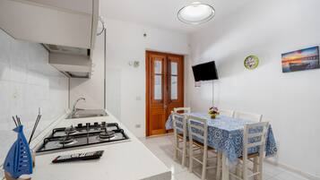 A kitchen with a gas stove, a sink, and a dining area with a table and chairs.