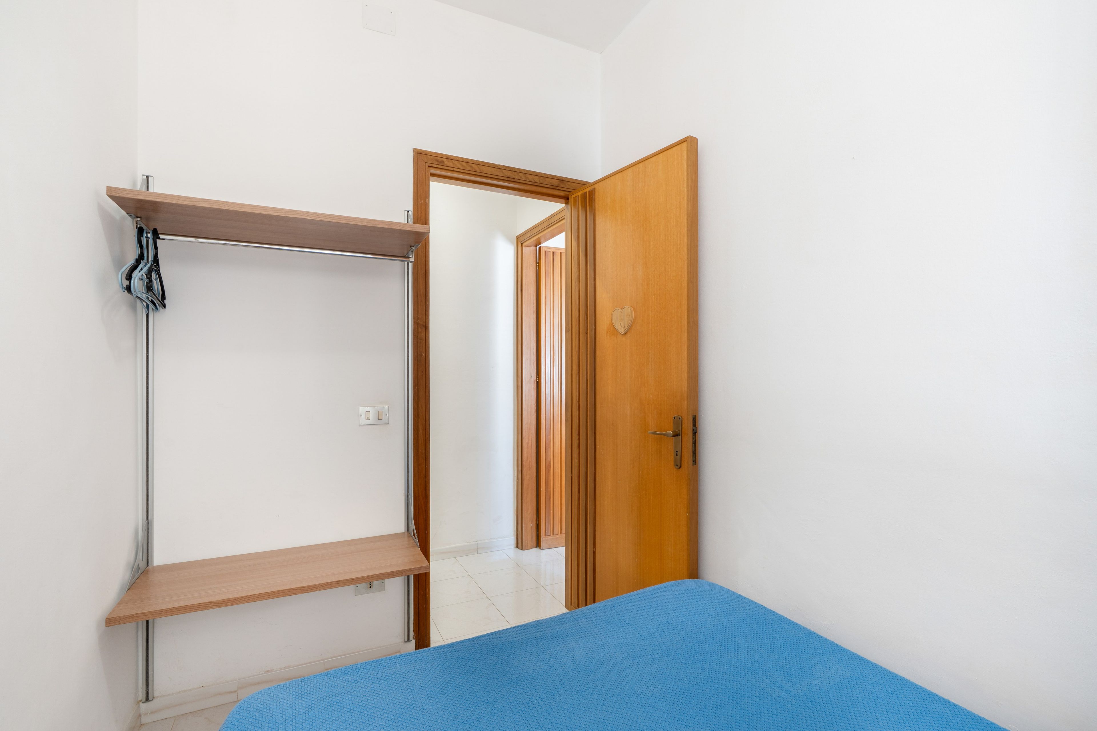 Une pièce avec un lit, une armoire en bois et une porte.