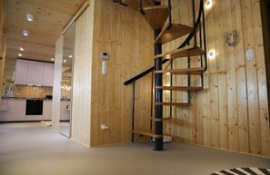 Ein Holzinnenraum mit einer Wendeltreppe, einem Küchenbereich im Hintergrund und einem modernen Design.