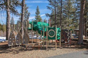 A playground with climbing structures and slides, surrounded by trees. - Spike's Place at Tahoe Donner by Tahoe Getaways - 2BR w 2 Bonus Rooms & Walking Distance to HOA! (Truckee)