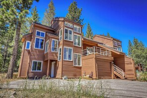 A multi-story wooden cabin with a balcony and a staircase. - Spike's Place at Tahoe Donner by Tahoe Getaways - 2BR w 2 Bonus Rooms & Walking Distance to HOA! (Truckee)