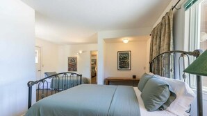Een slaapkamer met een bed, nachtkastje, lamp en een raam met gordijnen.