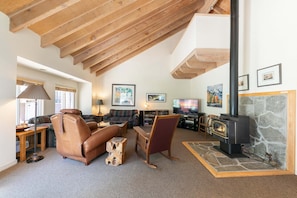 A spacious living room with a high ceiling, a fireplace, and a television. - Spike's Place at Tahoe Donner by Tahoe Getaways - 2BR w 2 Bonus Rooms & Walking Distance to HOA! (Truckee)